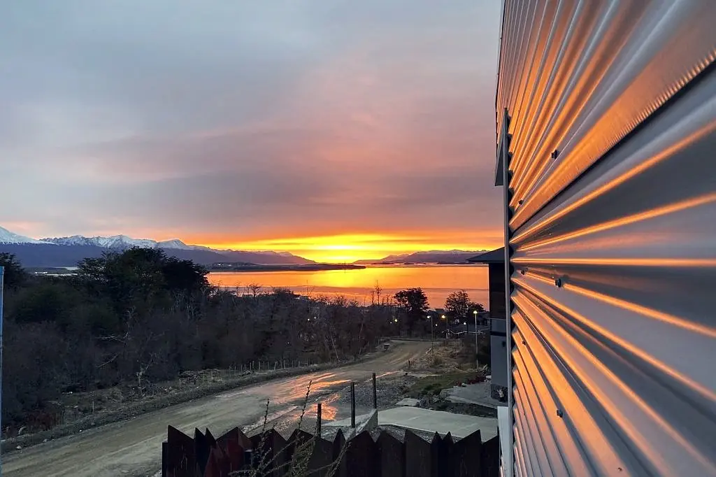 Amanecer sobre el canal Beagle reflejado en la chapa acanalada de la fachada