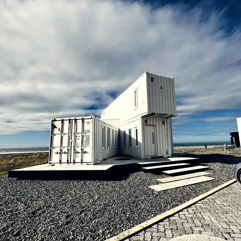 Casa de contenedores blancos sobre plataforma frente al mar, Tierra del Fuego