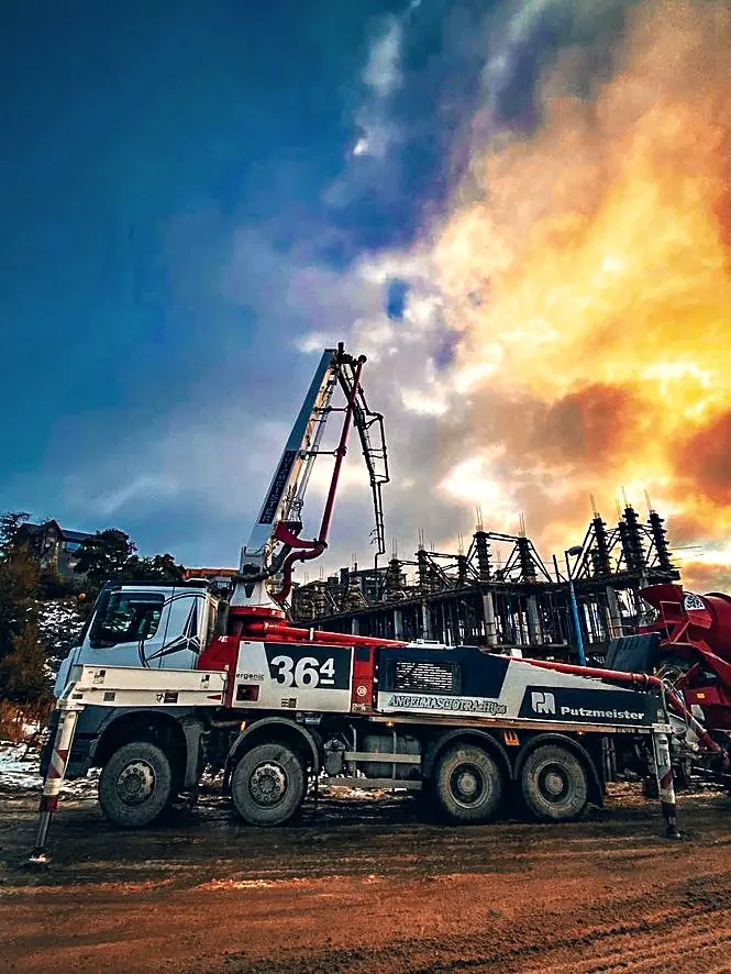 Bomba de hormigón frente a la estructura en obra, bajo un cielo de tormenta