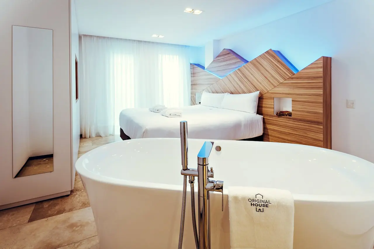 Habitación con bañera exenta y cabecero de madera