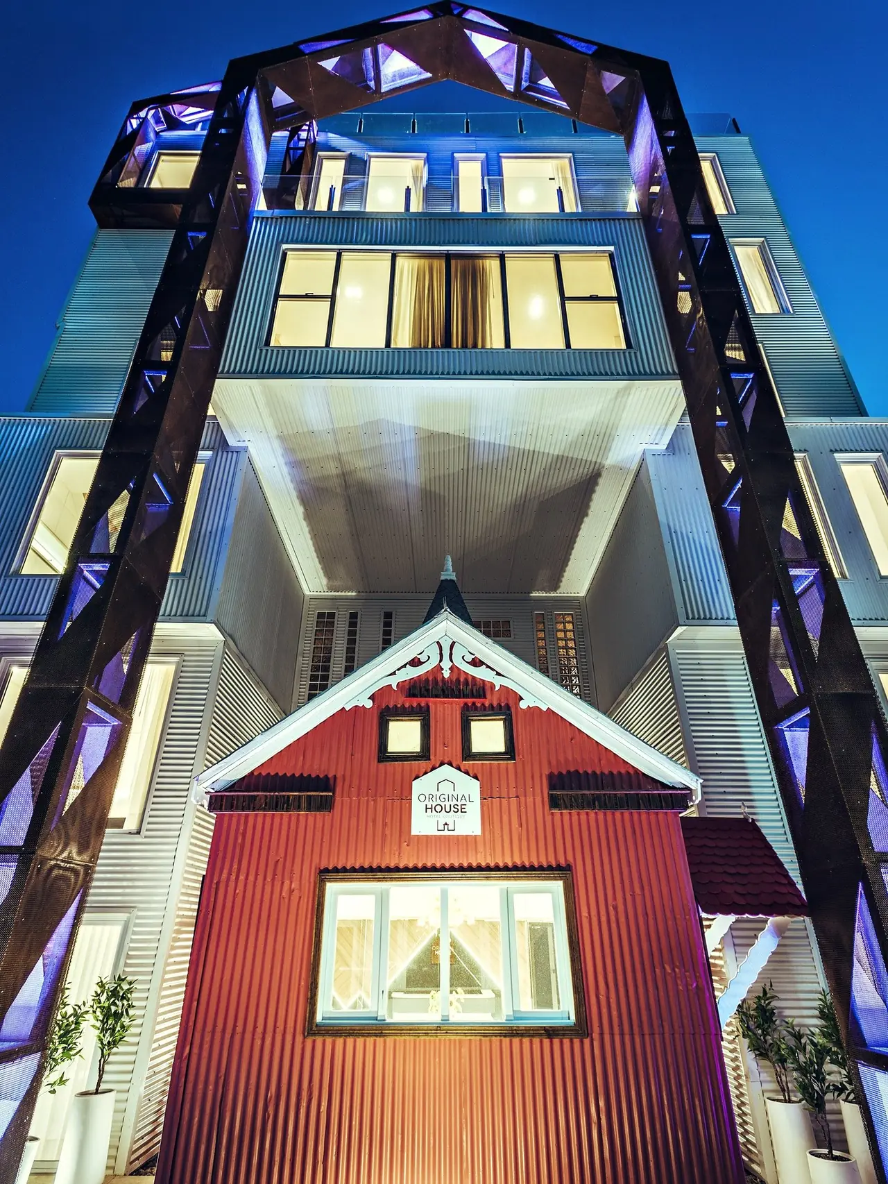 Original House en contrapicado de noche: la casa roja iluminada bajo los pórticos