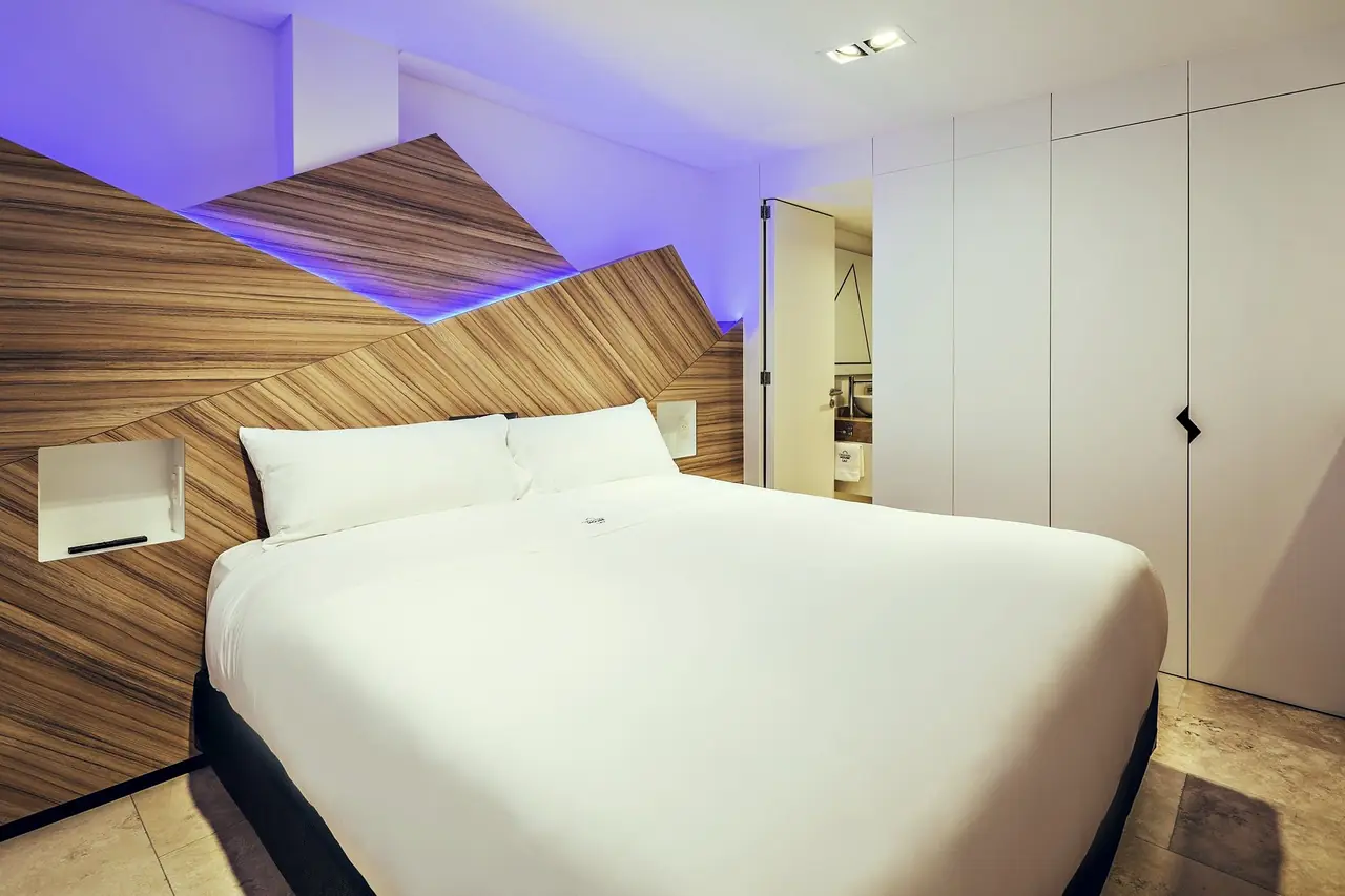 Dormitorio de Original House con cabecero de madera plegada y luz violeta