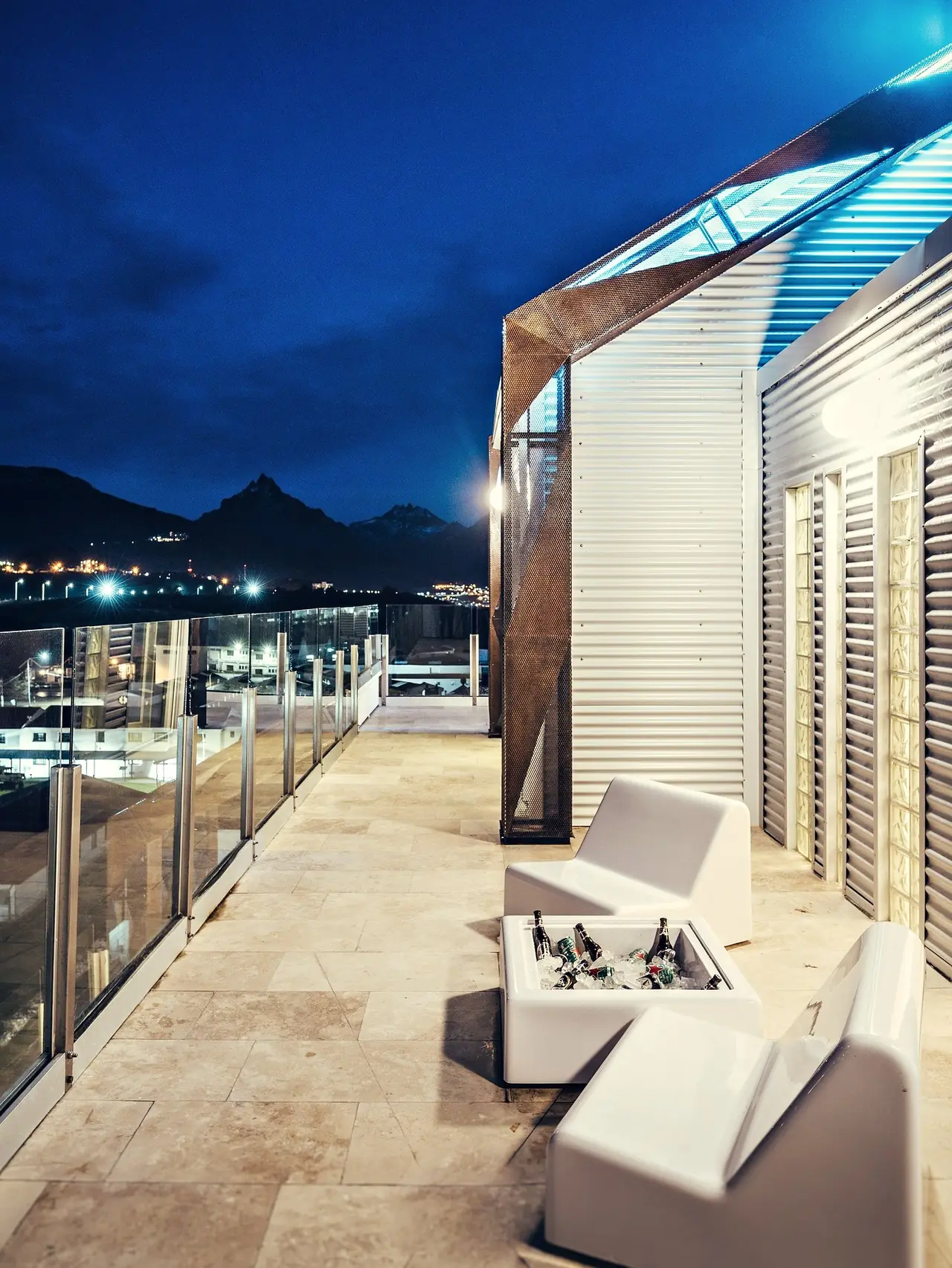 Terraza de Original House de noche con los pórticos iluminados y la ciudad al fondo