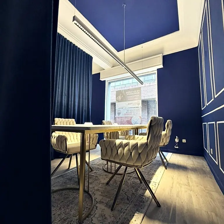 Sala de reuniones de RE/MAX Select en Madrid: paredes azul noche con molduras, mesa de mármol y sillas trenzadas